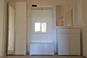 A room with a white wardrobe, a bench, and a mirror. - Cottage on the mudflats (Nebel auf Amrum)