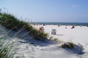 A sandy beach with a lifeguard tower and beachgoers. - Cottage on the mudflats (Nebel auf Amrum)