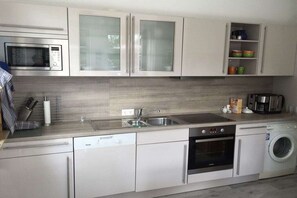 A modern kitchen with a microwave, oven, dishwasher, and washing machine. - Cottage on the mudflats (Nebel auf Amrum)