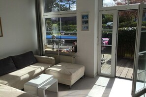 A modern living room with a sofa, a small table, and a sliding glass door leading to an outdoor area. - Cottage on the mudflats (Nebel auf Amrum)