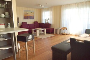 Ein Wohnzimmer mit einer Couch, einem Couchtisch und einem Essbereich mit Tisch und Stühlen.