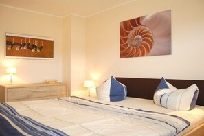 Ein Hotelzimmer mit einem Bett, zwei Nachttischlampen, einem Holznachttisch und zwei an der Wand hängenden Bildern.