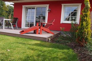 A red house with a deck, two windows, and a chair. - Boddenhus "Crane Rest" (Born am Darss)