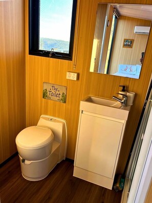 A compact bathroom with a toilet, sink, and a mirror.