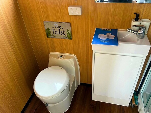 Een kleine badkamer met een toilet, een wastafel en een zeepdispenser.