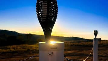A microphone on a stand with a chain, set against a sunset background.