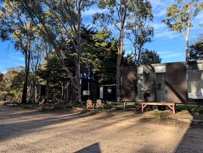 A campsite with a wooden structure, two chairs, and a bench.