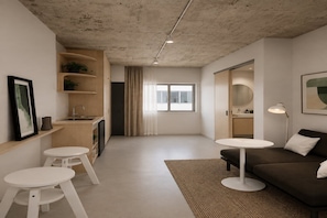 A modern living room with a sofa, two white tables, a rug, and a kitchen area with a sink and cabinets. - City Centre Studio with Rooftop Deck (Darwin City)