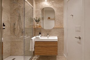 A modern bathroom with a glass-enclosed shower, a wooden vanity, and a mirror above the sink. - Darwin CBD Studio with Air Conditioning (Darwin City)
