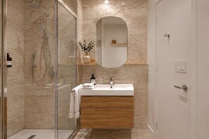 Ein modernes Badezimmer mit einer gläsernen Duschkabine, einem Holzbadezimmermöbel und einem Spiegel über dem Waschbecken.
