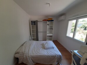 A bedroom with a bed, a wardrobe, and a window. - Spacious, fully equipped house surrounded by greenery, with a pool and a wood stove—perfect for families! (Cestas)