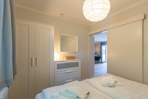 A hotel room with a bed, a dresser, a mirror, and a door leading to another room. - 1 "Seestern" in Haus Colonia (ID 292) (St. Peter-Bad)