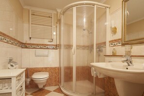 Ein Badezimmer mit einer Duschkabine, einem Waschbecken, einer Toilette und einem Spiegel.