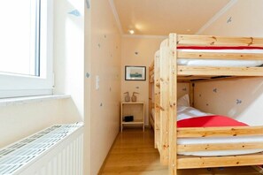 Ein Schlafraum mit Etagenbetten, einem Heizkörper, einer kleinen Ablage mit Dekoration und einem gerahmten Bild an der Wand.