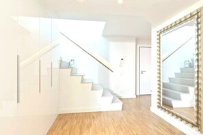 Ein modernes Interieur mit Treppe, einer Tür und einem großen Spiegel.