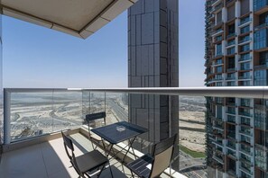 Ein Balkon mit Tisch und Stühlen, mit Blick auf eine Baustelle und die Stadtlandschaft.