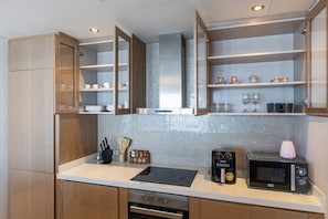 Eine moderne Küche mit Holzschränken, einer Mikrowelle, einer Kaffeemaschine und einer gefliesten Spritzschutzwand.