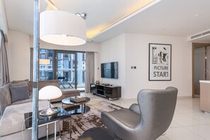 Ein modernes Wohnzimmer mit Sofa, Sessel, Couchtisch und Fernseher.