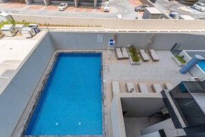 Ein Pool auf dem Dach mit Blick auf die Umgebung, darunter geparkte Autos und eine Straße.