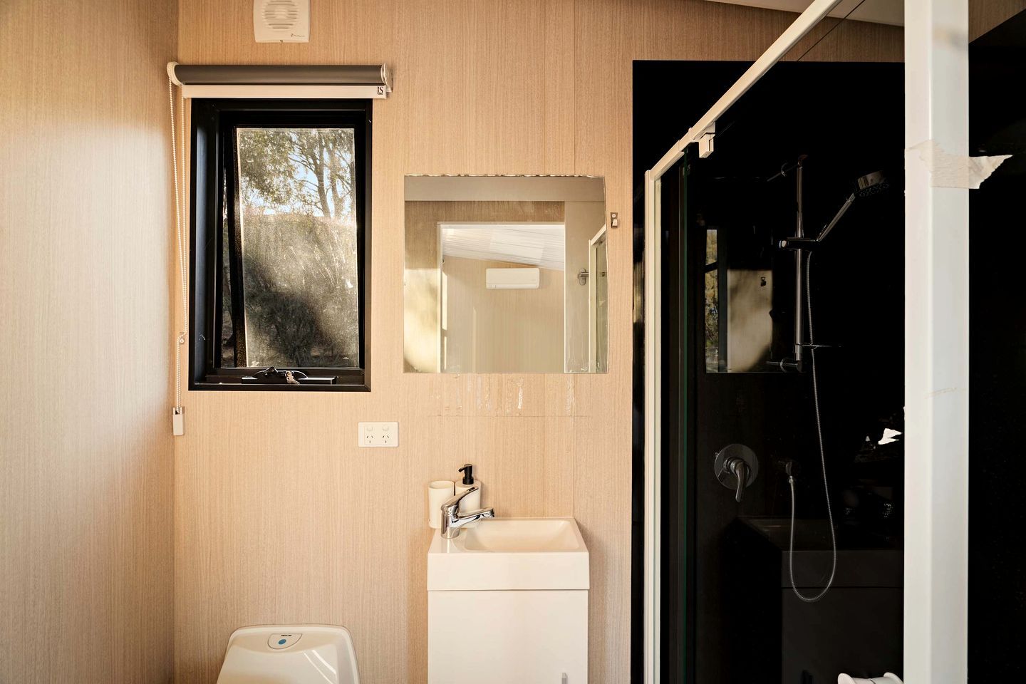 A compact bathroom with a window, a sink, and a shower.