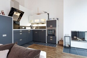 Eine moderne Küche mit integrierten Geräten, ein Essbereich mit einer Couch und ein Kamin.