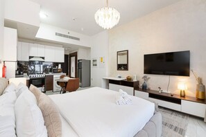 Ett modernt hotellrum med en säng, en TV, ett skrivbord och ett litet pentry.