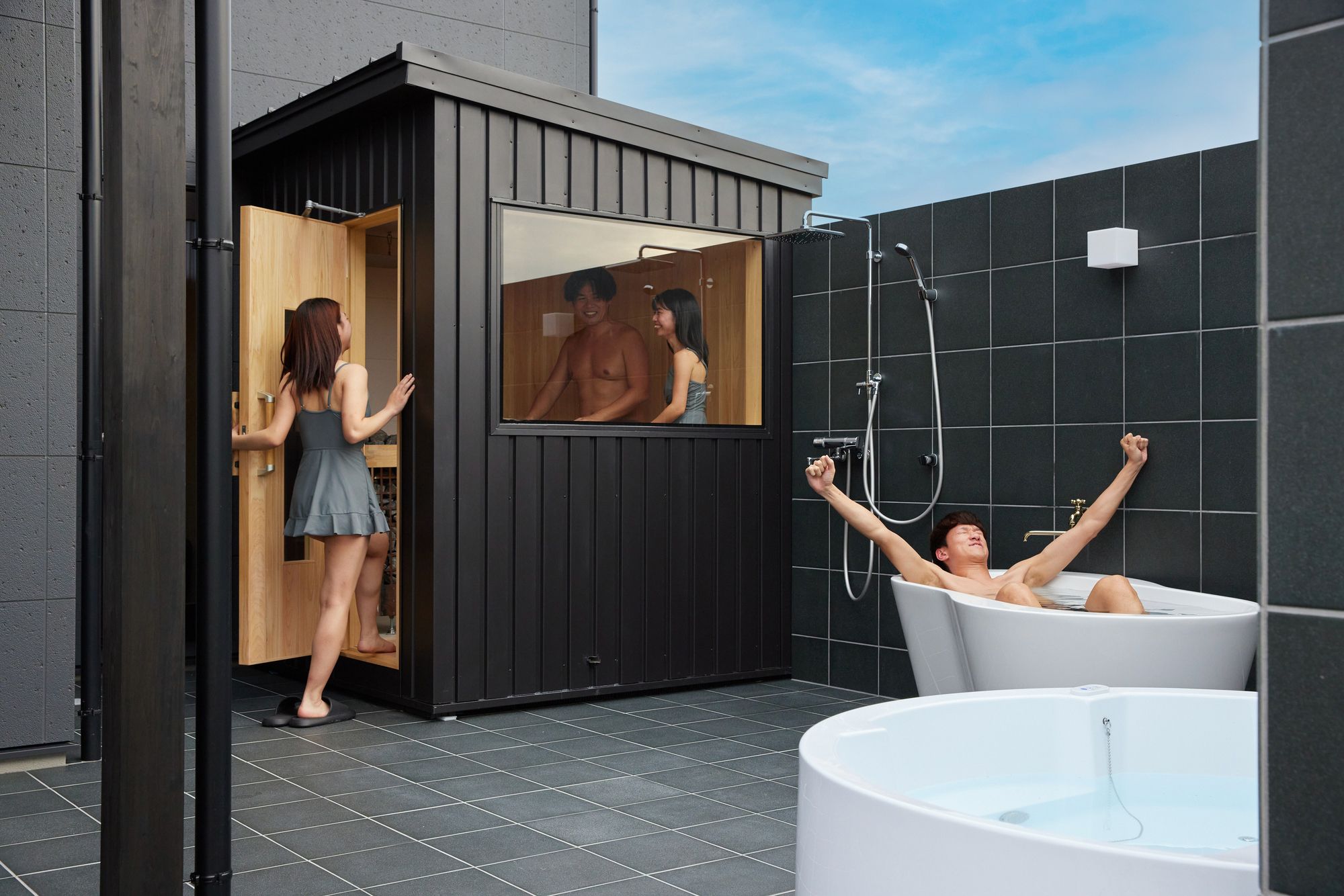 Un baño exterior moderno con estructura de cabaña de madera, una bañera y una zona de ducha.