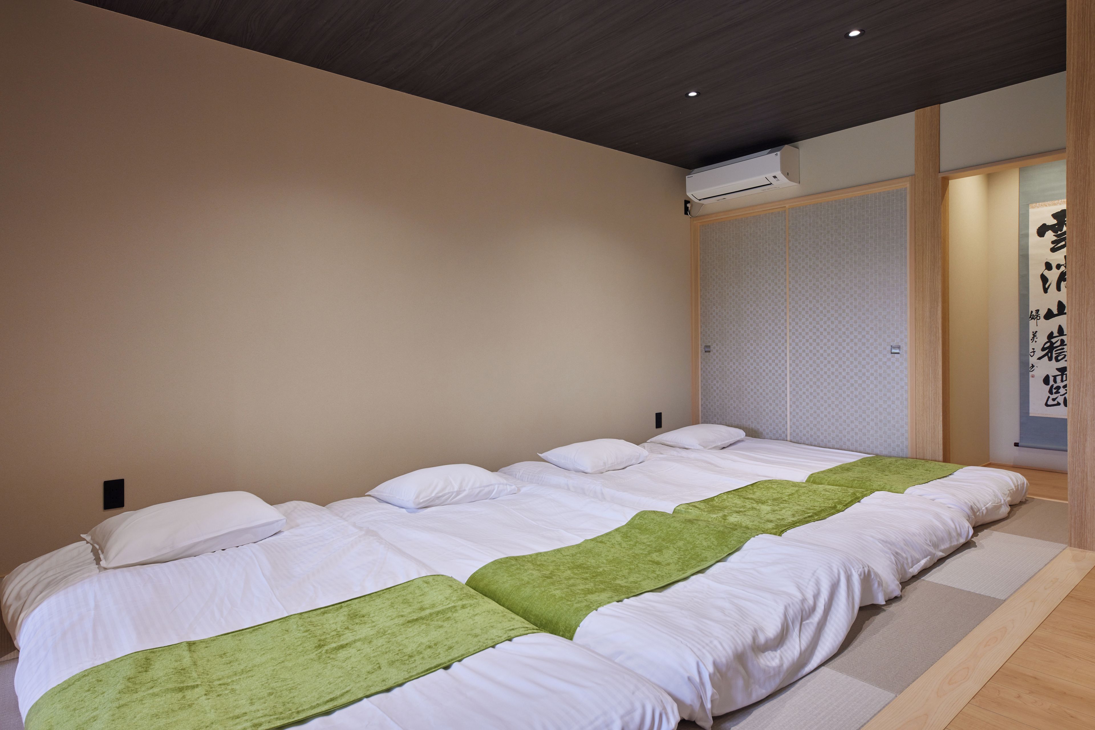 Una habitación de hotel con una cama grande, piso de madera y aire acondicionado instalado en la pared.