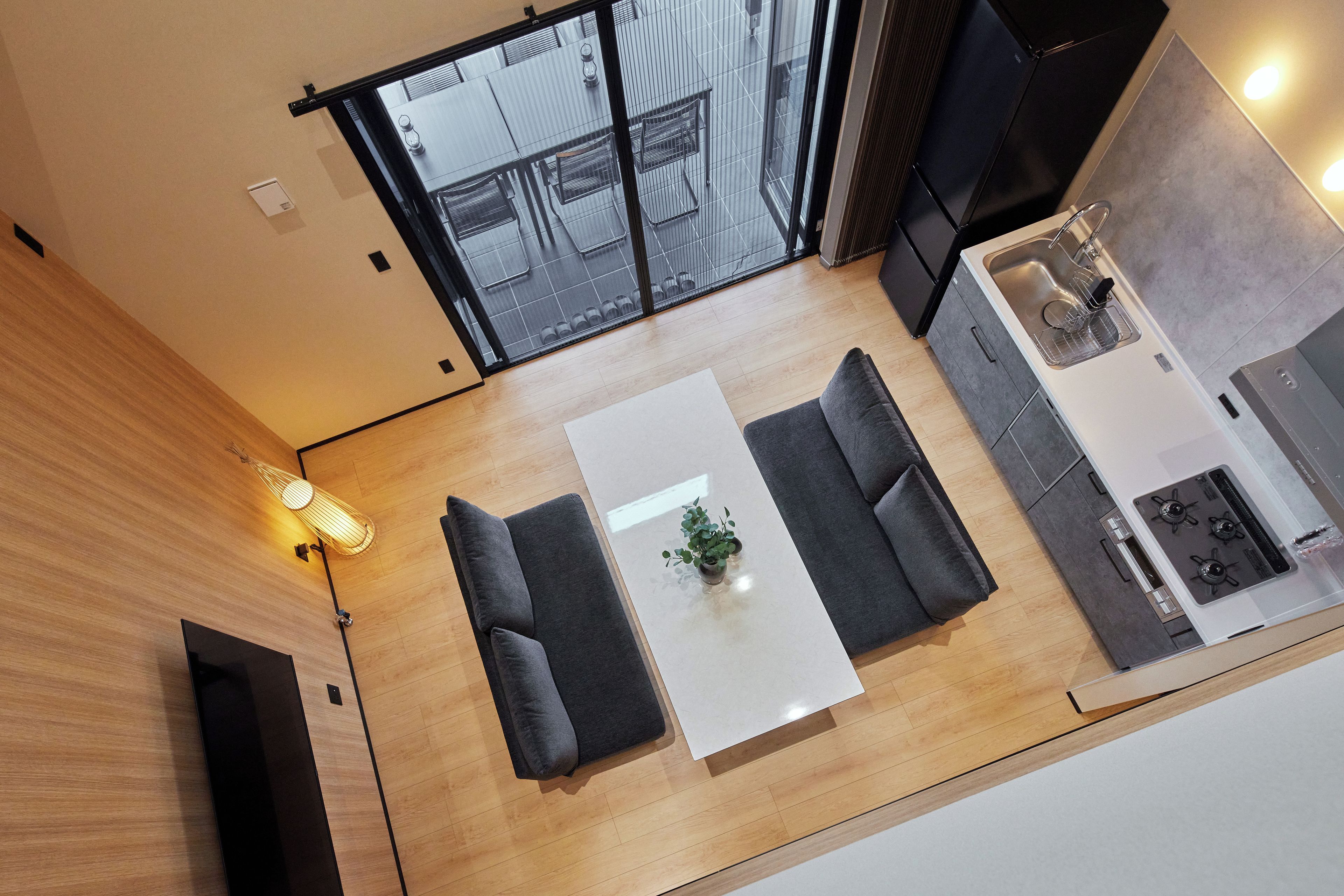 Una cocina moderna con estufa, pileta y comedor con mesa blanca y sofás grises.