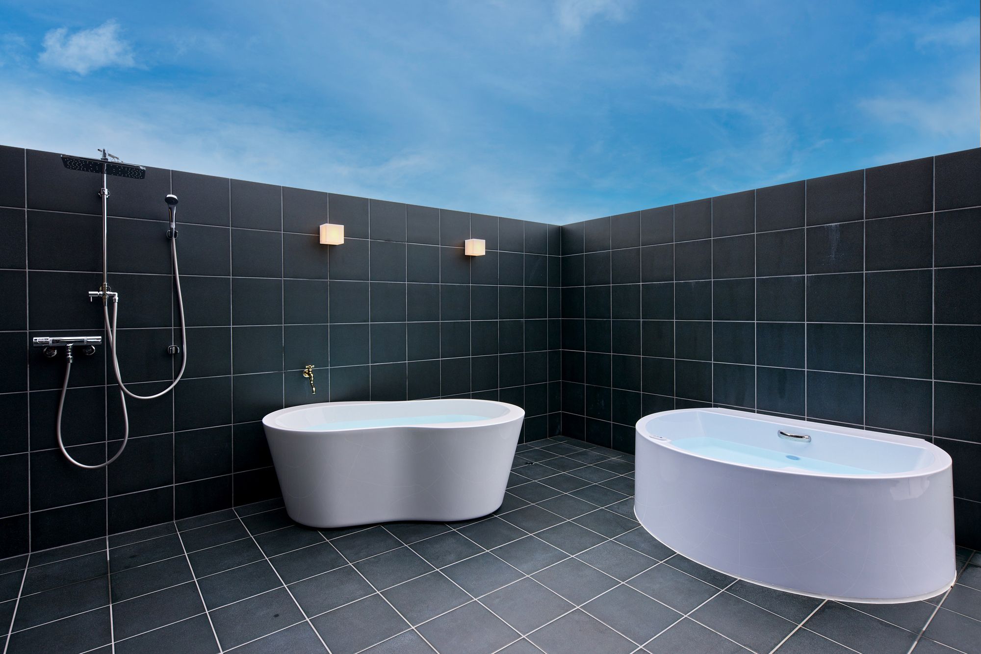 A modern bathroom with two freestanding tubs, a shower, and a tiled floor.