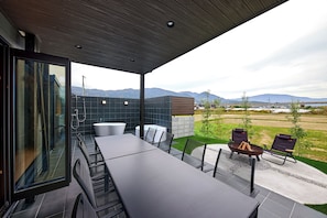 A modern outdoor patio with a dining table, chairs, a hot tub, and a view of the countryside. - SUITE VILLA -SHOU- (Takashima-shi,)