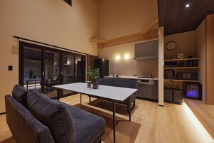 A modern kitchen with a dining area, a sofa, and a coffee machine.