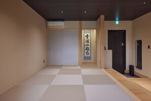 A hotel hallway with a checkered floor, a sliding door, and a wall-mounted sign with Japanese characters.