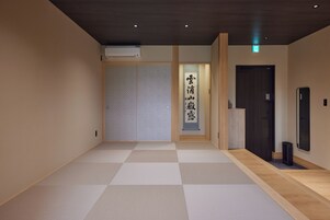 Ein Hotelgang mit Schachbrettmuster, einer Schiebetür und einem an der Wand befestigten Schild mit japanischen Schriftzeichen.
