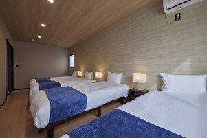 A hotel room with two beds, a window, and a wall-mounted air conditioner.