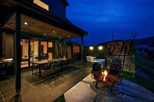 An outdoor patio with a fire pit, dining area, and a covered seating space.