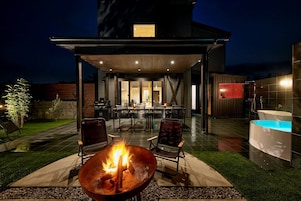 Un patio exterior con una chimenea, asientos, piscina y una zona de comedor cubierta.