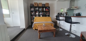 A compact room with a bed, a small table with a candle, a bookshelf, and a kitchenette area. - Route du Rhum with a Sea View in Dinard (Dinard)
