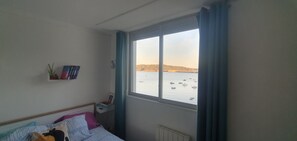 Ein Schlafzimmer mit einem großen Fenster mit Blick auf ein Gewässer und Boote.