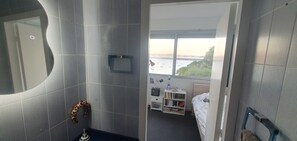Ein Zimmer mit Blick auf ein Gewässer, einem Bücherregal und einem Bett.