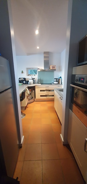 Eine moderne Küche mit Kühlschrank, Backofen und Mikrowelle. Über der Spüle befindet sich ein Fenster und es gibt einen Schrank mit einem Herd.