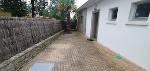 A narrow paved pathway leading to a building with a stone wall on one side and a white wall on the other. - Route du Rhum with a Sea View in Dinard (Dinard)