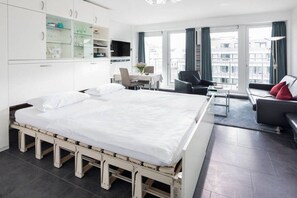 Ein Hotelzimmer mit Bett, Schreibtisch, Sofa und Blick auf die Stadt.