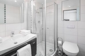Ein modernes Badezimmer mit einer Duschkabine, einem weißen Waschbecken und einer Toilette.