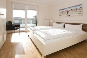 Ein modernes Hotelzimmer mit einem großen Bett, einem Schreibtisch und Blick auf die Stadt vom Balkon aus.