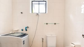 Un baño pequeño con inodoro, lavadora y un ventanal.