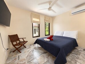 A hotel room with a bed, a chair, a ceiling fan, and a TV. - Charming Thai Mountain Villa (MVV) (Kathu)