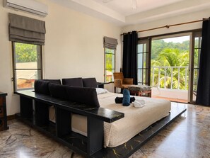 Een slaapkamer met een groot bed, een nachtkastje, een stoel en uitzicht op groen buiten het raam.