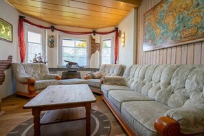 A cozy living room with a large sofa, two armchairs, a coffee table, and a world map on the wall. - Holiday home in Büsum with swimming pool (Büsum)