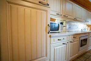 A kitchen with white cabinetry, a microwave, a coffee maker, and an oven. - Holiday home in Büsum with swimming pool (Büsum)